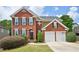Charming two-story brick home featuring a well-manicured lawn, black shutters, and a two-car garage at 75 Vinings Lake Sw Dr, Mableton, GA 30126