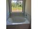 Soaking tub with tile surround is positioned under a window at 3036 Zodiac Ct, Lawrenceville, GA 30044