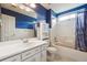 Bathroom featuring blue walls, a white vanity, and a tub-shower combo with curtain at 3715 Frankie Wade Ln, Loganville, GA 30052