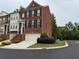 Brick townhome featuring an attached garage, small shrubbery, and a view of the tree-lined street at 4888 Colchester Se Ct # 3, Atlanta, GA 30080