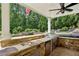Outdoor kitchen with built-in grill, beverage cooler, stone countertops, and views of the waterfall pool at 520 Flying Scot Way, Alpharetta, GA 30005