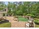 A backyard featuring a custom pool, hot tub, stone patio, outdoor seating, and mature trees at 520 Flying Scot Way, Alpharetta, GA 30005