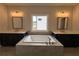 Bathroom featuring soaking tub with tile surround and double sinks with modern lighting at 173 Basil St, Cumming, GA 30040