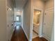 Hallway with hardwood floors leading to a bathroom with double sinks and various rooms at 173 Basil St, Cumming, GA 30040