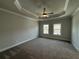 Spacious main bedroom with tray ceiling, ceiling fan, carpet, and windows at 173 Basil St, Cumming, GA 30040