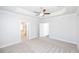 Spacious main bedroom with carpet, a ceiling fan, tray ceiling, and ensuite bathroom access at 173 Basil St, Cumming, GA 30040