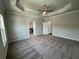 Spacious main bedroom with tray ceiling, ceiling fan, carpet, and open doorway to bathroom at 173 Basil St, Cumming, GA 30040