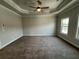 Large bedroom featuring a ceiling fan, tray ceiling, carpet flooring, and ample natural light at 173 Basil St, Cumming, GA 30040