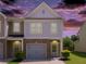 Charming townhouse featuring a brick facade, one-car garage, manicured lawn, and welcoming front door at dusk at 4925 Longview Walk, Decatur, GA 30035