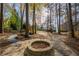 Stone fire pit in the backyard, surrounded by trees, creates an inviting outdoor gathering spot for cool evenings at 2410 Emerald Dr, Loganville, GA 30052