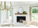 Bright living room with a white painted fireplace, wood mantle and modern chandelier at 1662 Rainier Falls Ne Dr, Atlanta, GA 30329