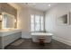 Bright bathroom showcasing a soaking tub, herringbone tile floor, and a vanity with a well-lit mirror at 316 S Esplanade, Alpharetta, GA 30009