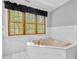 Bathroom featuring a soaking tub, wooden window trim, white marble tile, and recessed lighting at 5302 Greenway Dr, Villa Rica, GA 30180