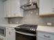 Close-up of the kitchen area featuring stainless steel appliances and stylish herringbone tile backsplash at 1976 Deco Dr, Kennesaw, GA 30144