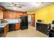 Cozy kitchen with wood cabinets, black appliances, and a bright yellow accent wall at 2100 Ann Se Ct, Conyers, GA 30013