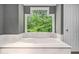 Close-up of a modern bathtub with a large window offering a view of lush greenery at 387 Nickajack Se Rd, Mableton, GA 30126