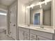 Bathroom with double vanity, white cabinets, large mirror with decorative lighting, and neutral tile flooring at 3745 Reserve Overlook (#30) Way, Cumming, GA 30041