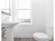 Bright bathroom with a white pedestal sink and toilet near a sunny window at 4253 Millcroft Pl # 198, Buford, GA 30518