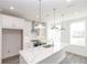 Bright, all-white kitchen features a large island with quartz countertop, stainless steel appliances, and pendant lighting at 4253 Millcroft Pl # 198, Buford, GA 30518
