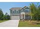 Charming two-story home featuring a stone and green-paneled facade, a two-car garage, and a well-manicured front lawn at 7252 Eton Ln, Locust Grove, GA 30248