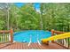 Backyard view of an above ground swimming pool with a slide and wooden deck at 4332 Brushy Mountain Rd, Rockmart, GA 30153