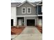 New construction townhome showing a gray and white exterior with a concrete driveway leading to a one-car garage at 9454 Pinecrest Path # 315, Jonesboro, GA 30238