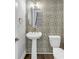 Stylish powder room featuring patterned wallpaper, pedestal sink, and modern fixtures at 2171 Burnside Dr Nw, Atlanta, GA 30318