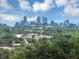 Stunning skyline view featuring modern buildings rising above lush green trees under a bright blue cloudy sky at 2171 Burnside Dr Nw, Atlanta, GA 30318