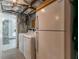 Laundry room with washer, dryer, and refrigerator in an unfinished basement with exposed pipes and a brick wall at 2406 Glenwood Ne Dr, Atlanta, GA 30305