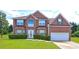 Charming two-story brick home with manicured lawn and attached two-car garage at 1506 Saint George Pl, Conyers, GA 30012