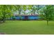 Large, lush backyard with mature trees surrounding a blue home with back patio at 5742 Harbor Dr, Buford, GA 30518