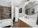 Modern bathroom featuring elegant vanity, storage cabinet, and shower-tub combo with decorative accent wall at 5742 Harbor Dr, Buford, GA 30518