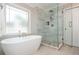 Bright bathroom featuring a soaking tub and glass shower, complimented by a bright, frosted window at 1161 Arborhill Dr, Woodstock, GA 30189