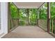 Relaxing covered deck with wood floors and railing features a serene view surrounded by lush greenery at 1161 Arborhill Dr, Woodstock, GA 30189