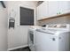 Modern laundry room featuring white front-load washer and dryer, stylish cabinets, and black tile floors at 1161 Arborhill Dr, Woodstock, GA 30189