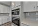 Close up of stainless steel double ovens and gray subway tile backsplash in modern kitchen at 3968 Annsbury Court, Lilburn, GA 30047