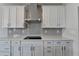 Modern kitchen featuring white cabinets, stainless steel range hood, and a gray subway tile backsplash at 3968 Annsbury Court, Lilburn, GA 30047