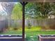 View of the backyard with wood fence, green grass, flower beds, and beautiful trees at 702 Emeril Dr, Avondale Estates, GA 30002