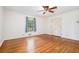 A bright bedroom with hardwood floors, a ceiling fan, and a window dressed with patterned blue curtains at 2790 Westhampton Way, Tucker, GA 30084