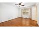 An empty bedroom with hardwood floors, a window with blinds and light-colored curtains, and a white door at 2790 Westhampton Way, Tucker, GA 30084
