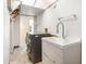 This laundry room features a washer and dryer and a sink with a chrome faucet, with overhead storage and neutral tones at 2790 Westhampton Way, Tucker, GA 30084