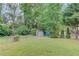 A large backyard featuring a storage building, trees, and a partial chain link fence at 1728 Hudson Rd, Decatur, GA 30033