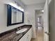 Bathroom featuring a granite countertop, framed mirror, and wood-look floors at 829 Longfellow Ct, Stone Mountain, GA 30088