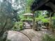 Picturesque backyard pond with a small bridge and lush landscaping viewed from a stone patio at 2038 Lee Se Rd, Smyrna, GA 30080