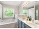 Bright bathroom featuring a large soaking tub, double sinks and a view of mature trees outside at 5830 Sterling Ct, Cumming, GA 30040
