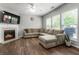 Comfortable living room featuring hardwood floors, a fireplace, and a large sectional sofa with natural light at 5830 Sterling Ct, Cumming, GA 30040