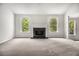 Spacious living room with a cozy fireplace, large windows, and neutral carpeting at 1024 Odelle Cir, Mcdonough, GA 30253