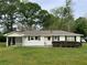 Charming single-story home with white siding, black shutters, and a covered carport nestled amongst mature trees at 66 Lakeshore Dr, Bowdon, GA 30108