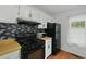 Kitchen featuring black appliances, white cabinetry, and a gas stove at 6420 Marbut Rd, Lithonia, GA 30058
