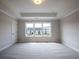 Spacious bedroom featuring a tray ceiling, plush carpeting, and a large window with neighborhood views at 1991 Deco Dr, Kennesaw, GA 30144